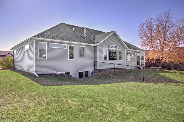 back of property featuring fence, a lawn, and roof with shingles