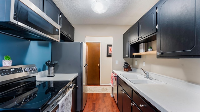 kitchen with dark wood-type flooring, appliances with stainless steel finishes, sink, and a textured ceiling