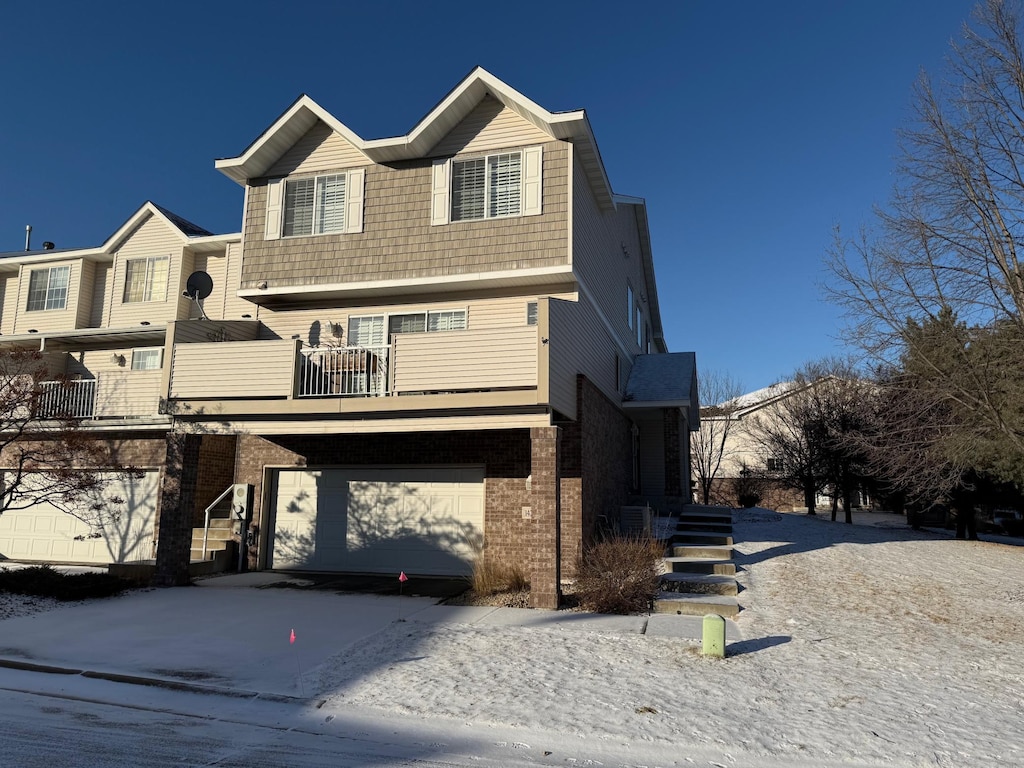 view of front of property featuring a garage, a balcony, and central AC unit