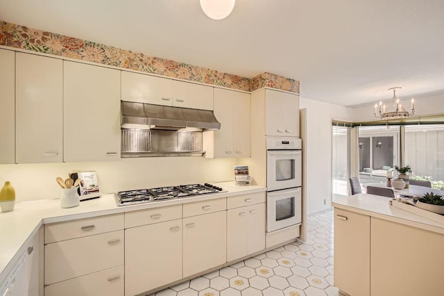 kitchen with light countertops, white appliances, an inviting chandelier, and under cabinet range hood