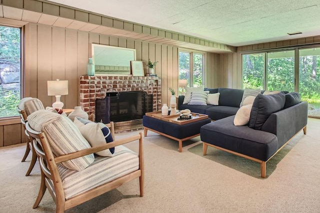 living area featuring plenty of natural light, wooden walls, a fireplace, and light colored carpet