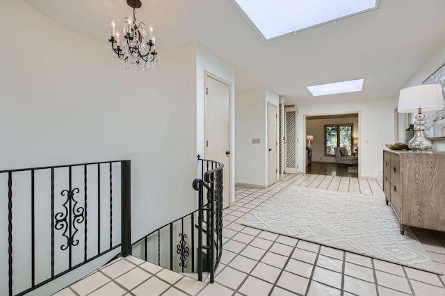 hallway featuring a skylight, a notable chandelier, and an upstairs landing