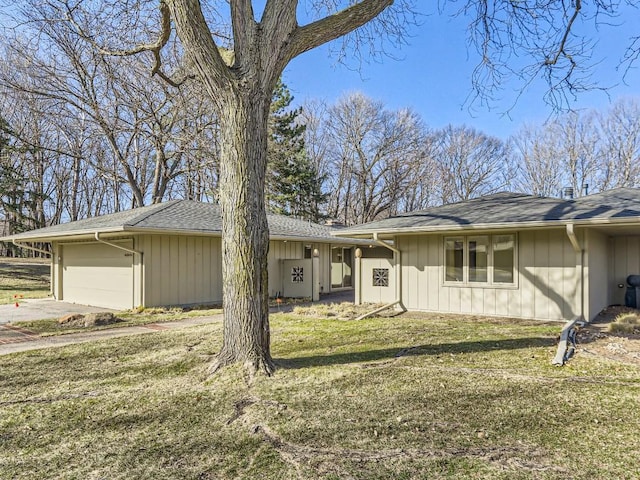 single story home with concrete driveway, a front lawn, roof with shingles, and an attached garage