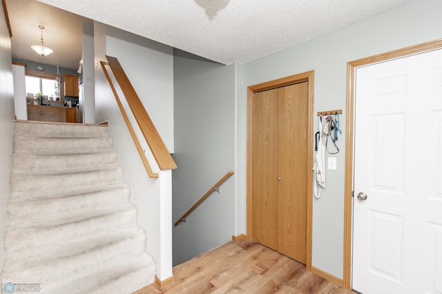 staircase with a textured ceiling and wood finished floors