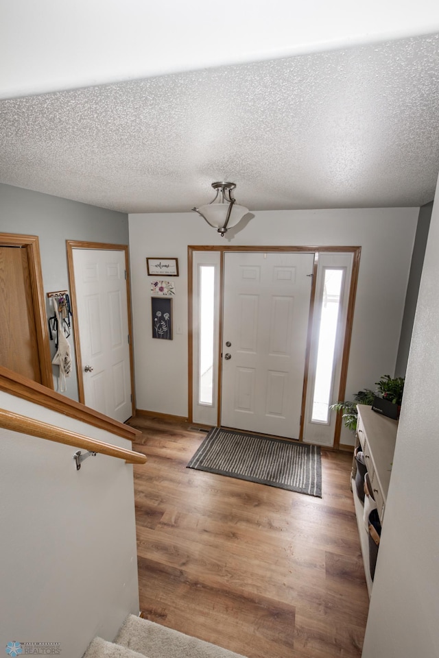 foyer entrance with a textured ceiling and light wood finished floors