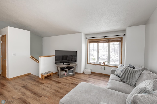 living area featuring light wood finished floors, baseboards, and a textured ceiling