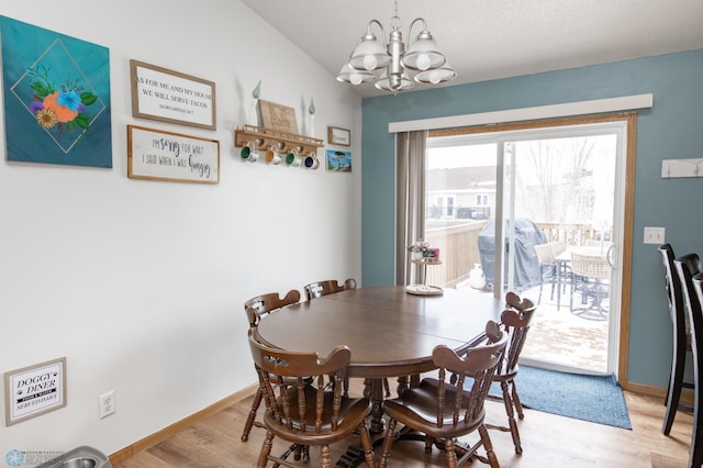 dining area featuring lofted ceiling, light wood finished floors, baseboards, and a notable chandelier