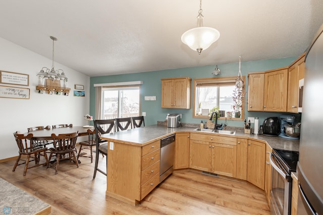 kitchen with light wood-style flooring, stainless steel appliances, a peninsula, a sink, and vaulted ceiling