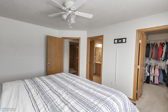 bedroom featuring light colored carpet, ceiling fan, a spacious closet, a textured ceiling, and a closet