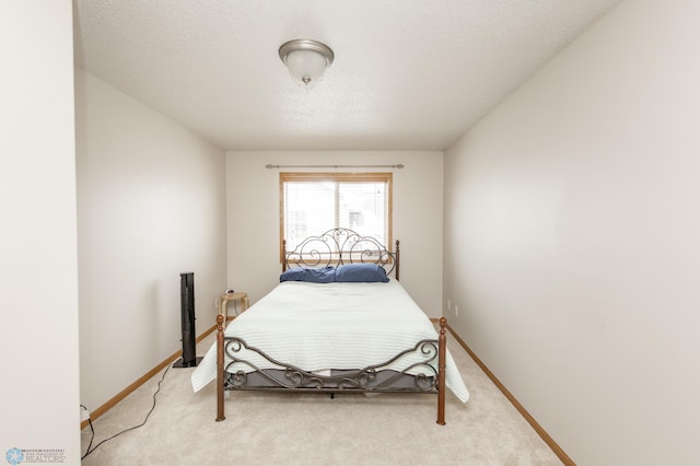 bedroom featuring baseboards, a textured ceiling, and light colored carpet