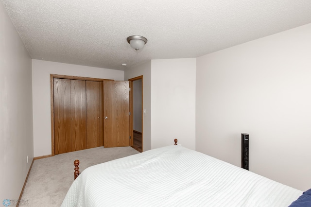 bedroom with a textured ceiling, carpet floors, and a closet