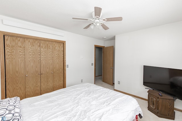 bedroom with a closet, light colored carpet, ceiling fan, and baseboards