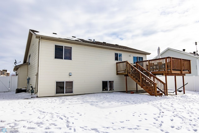 snow covered property with fence, a deck, and stairs