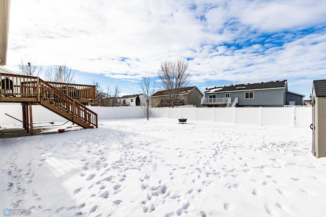 yard layered in snow with a fenced backyard, stairway, and a wooden deck