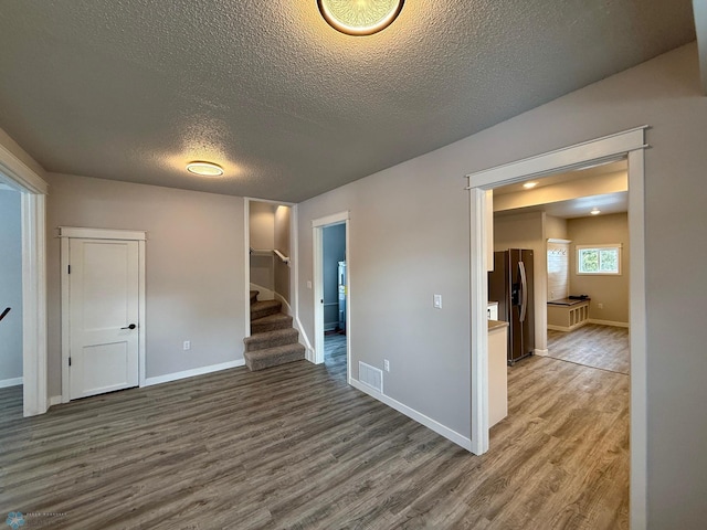 empty room with hardwood / wood-style floors and a textured ceiling