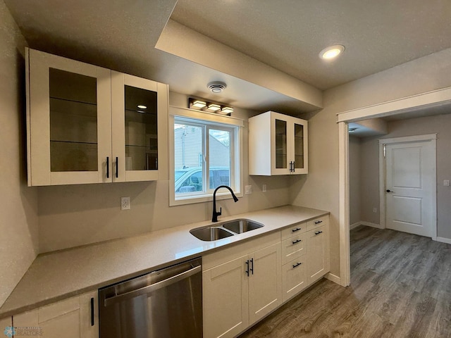 kitchen featuring hardwood / wood-style flooring, white cabinetry, sink, and stainless steel dishwasher