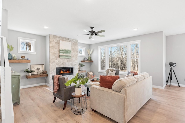 living room featuring a fireplace, light hardwood / wood-style floors, and ceiling fan