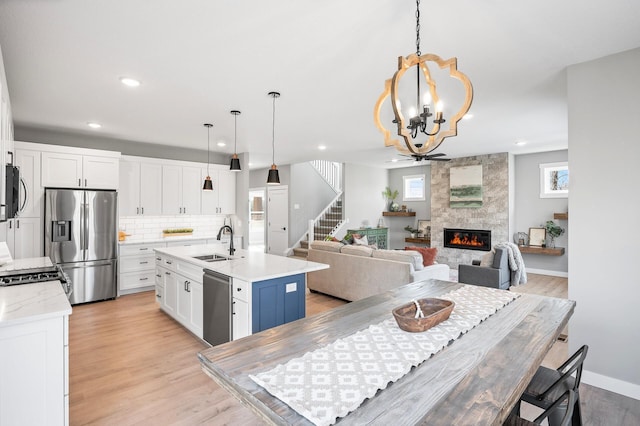 kitchen with stainless steel appliances, an island with sink, and white cabinets