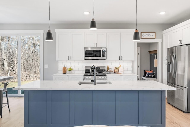 kitchen with pendant lighting, white cabinetry, appliances with stainless steel finishes, and an island with sink