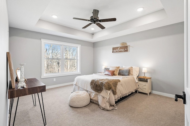 carpeted bedroom featuring ceiling fan and a tray ceiling