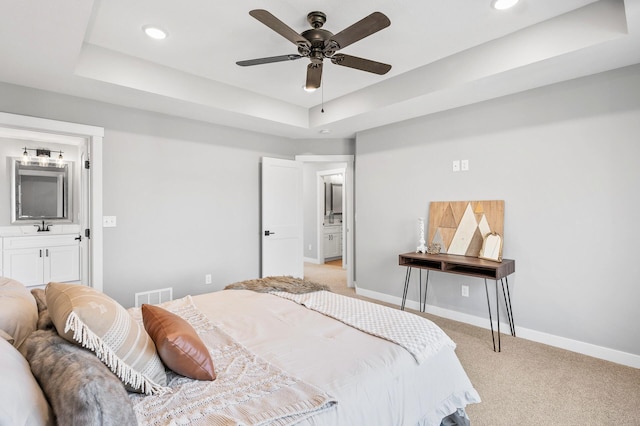 carpeted bedroom featuring ceiling fan, a raised ceiling, and sink