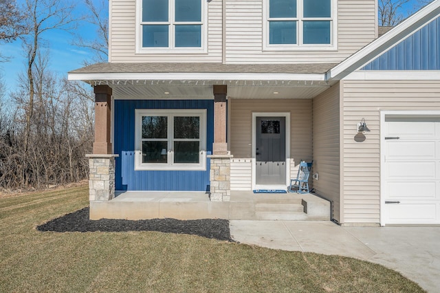 view of exterior entry featuring a garage, a yard, and covered porch