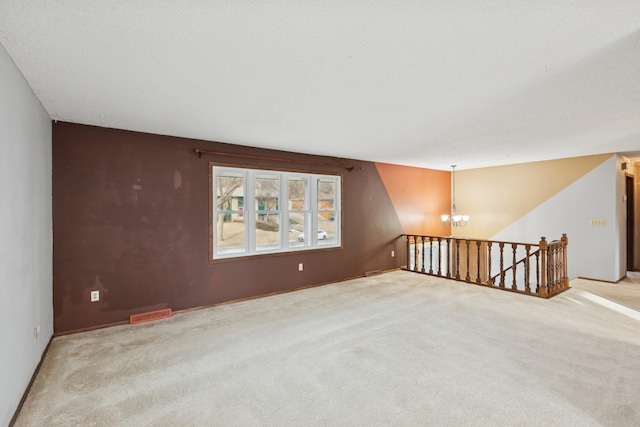 spare room featuring light colored carpet and a chandelier