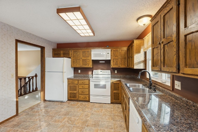 kitchen featuring white appliances, sink, and a textured ceiling