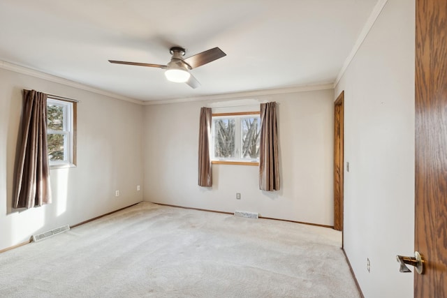 spare room with ceiling fan, light colored carpet, a healthy amount of sunlight, and ornamental molding