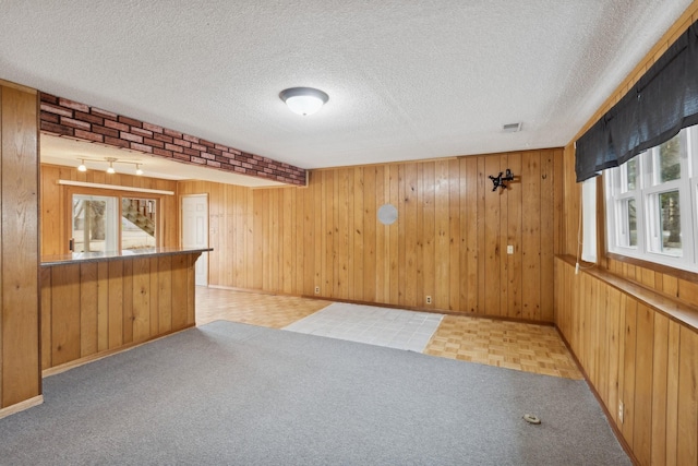 bar with wooden walls, light colored carpet, and a textured ceiling