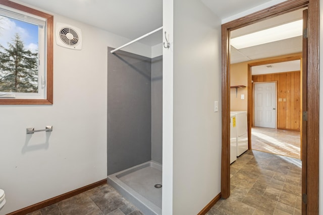 bathroom with walk in shower, wooden walls, and separate washer and dryer