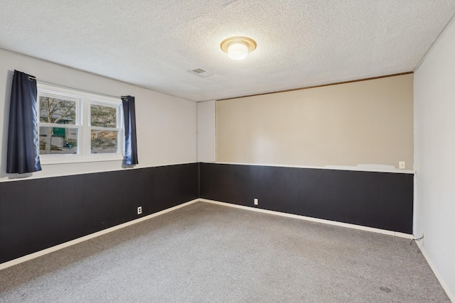 carpeted spare room featuring a textured ceiling and wood walls