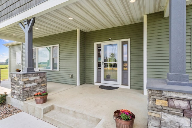 doorway to property with stone siding and a porch