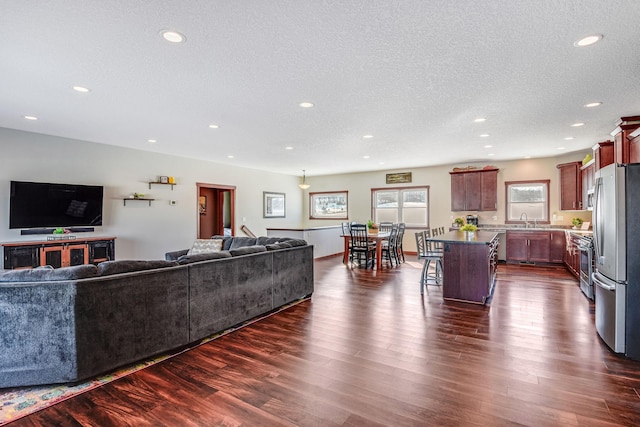 living area featuring recessed lighting, dark wood-style floors, and a textured ceiling