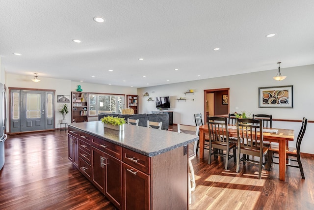 kitchen with dark countertops, dark brown cabinets, a center island, dark wood-style floors, and a textured ceiling