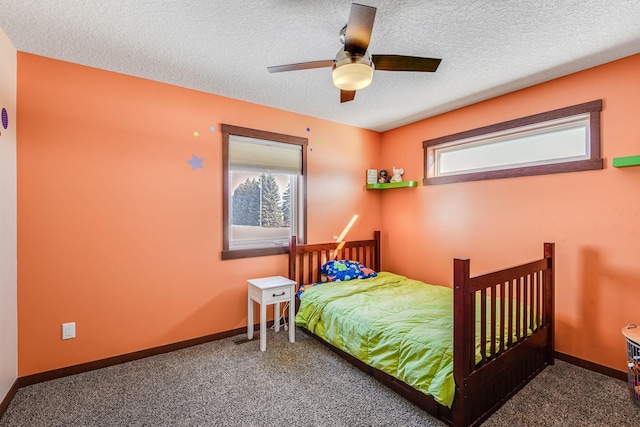 carpeted bedroom with ceiling fan, baseboards, and a textured ceiling