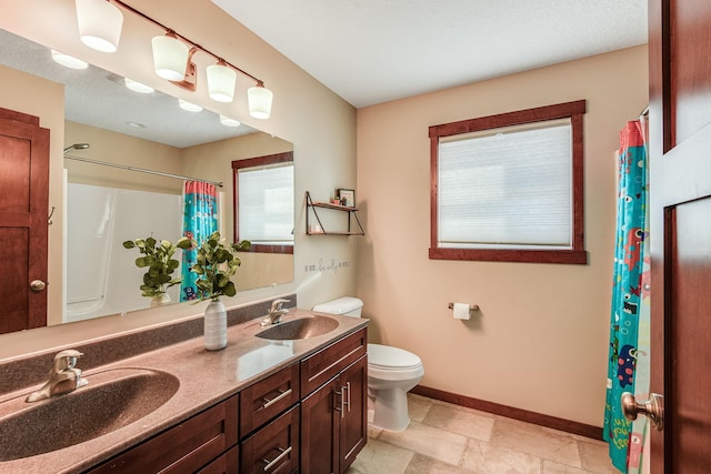 full bathroom with double vanity, toilet, baseboards, and a sink