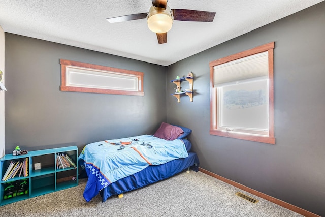 bedroom with a textured ceiling, carpet, visible vents, and baseboards