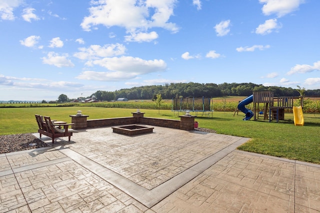 view of patio / terrace featuring a rural view, a trampoline, a fire pit, and playground community