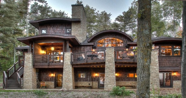 back of house with stairs, a balcony, and a chimney