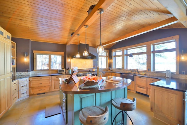 kitchen featuring vaulted ceiling with beams, wood counters, exhaust hood, a wealth of natural light, and a center island