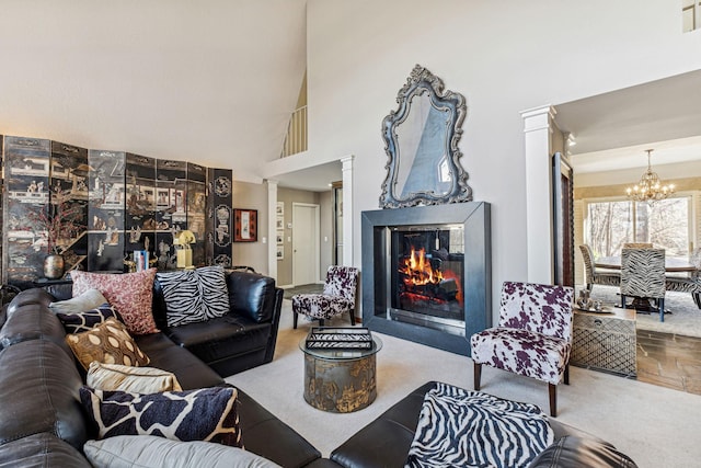 carpeted living room featuring a towering ceiling, decorative columns, and a chandelier