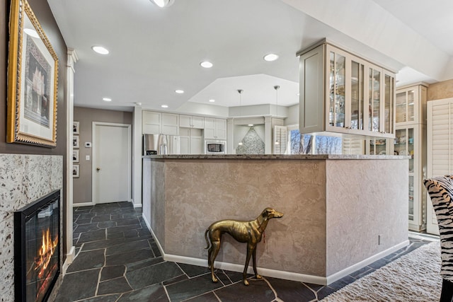 kitchen featuring stainless steel appliances, hanging light fixtures, stone counters, and kitchen peninsula