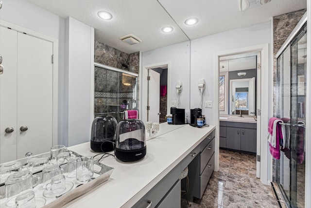 bathroom with vanity, a textured ceiling, and a shower with shower door