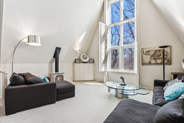 carpeted living room with a skylight, high vaulted ceiling, and a wood stove