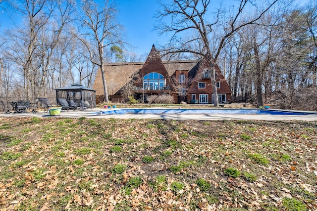 rear view of property featuring a gazebo, a patio area, and a covered pool