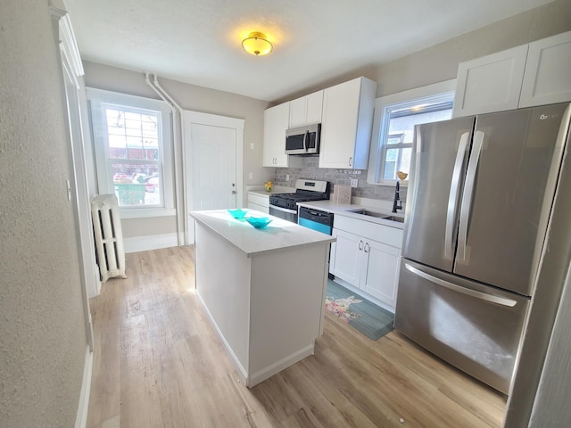 kitchen featuring sink, a center island, radiator heating unit, stainless steel appliances, and white cabinets