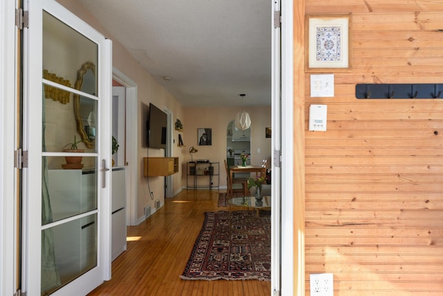 hall with hardwood / wood-style floors and wooden walls