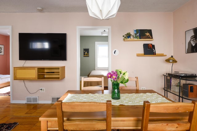 dining area with hardwood / wood-style flooring and a textured ceiling