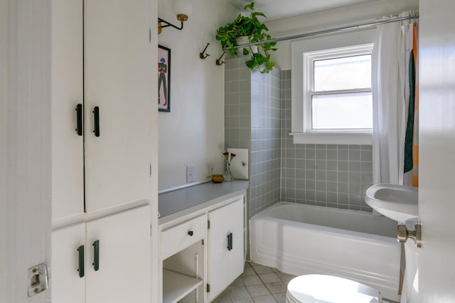 bathroom with tiled shower / bath combo, tile patterned floors, and toilet